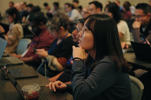 Attendees with laptops listen closely during a technical session