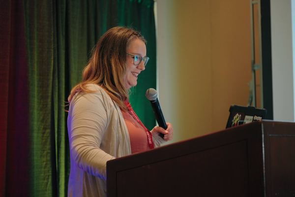 A speaker at the podium addresses the audience